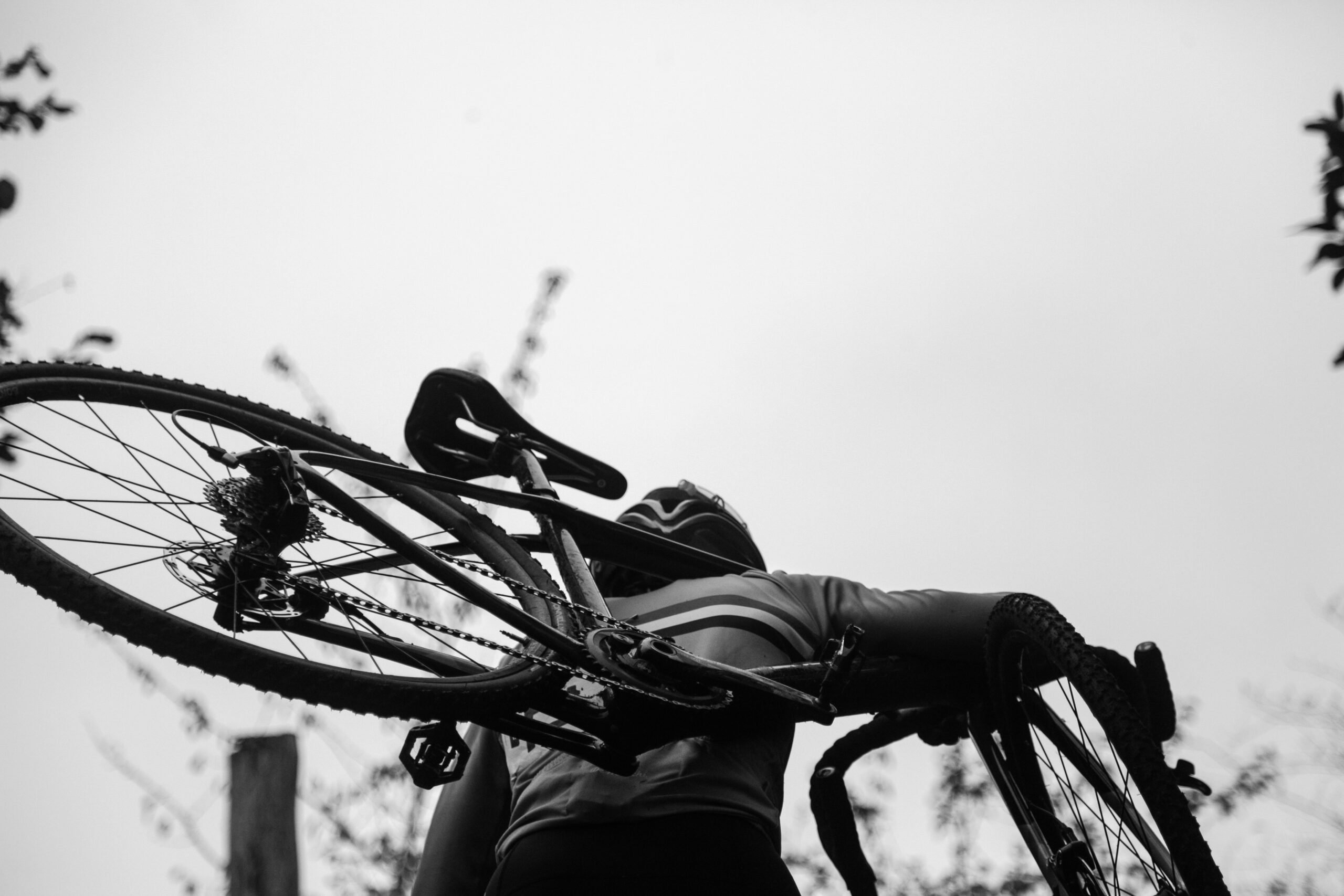 A cyclist with his bike on his shoulder in a cyclo-cross race.